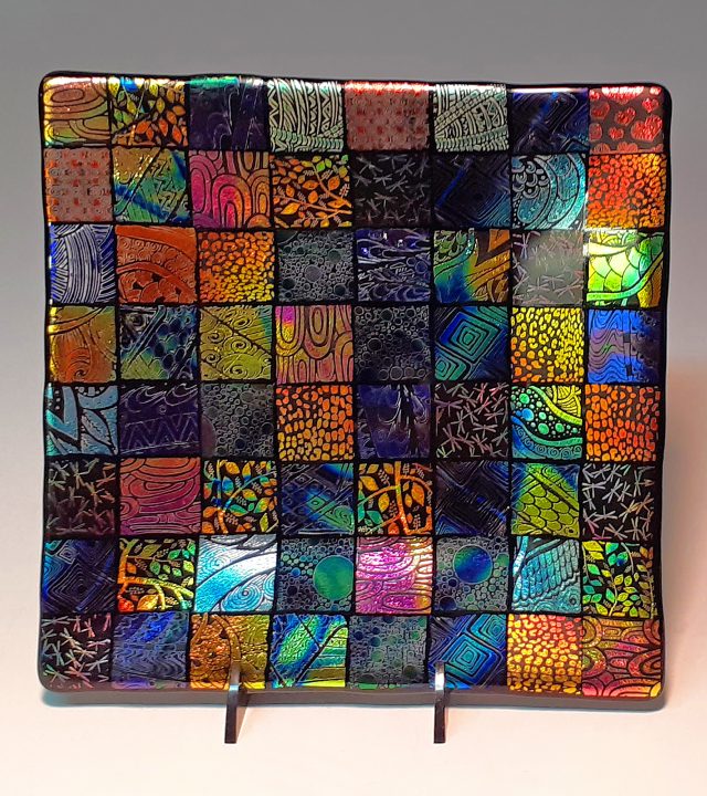 square plate patterned with 64 individual squares of brilliantly colored iridescent glass, each square different