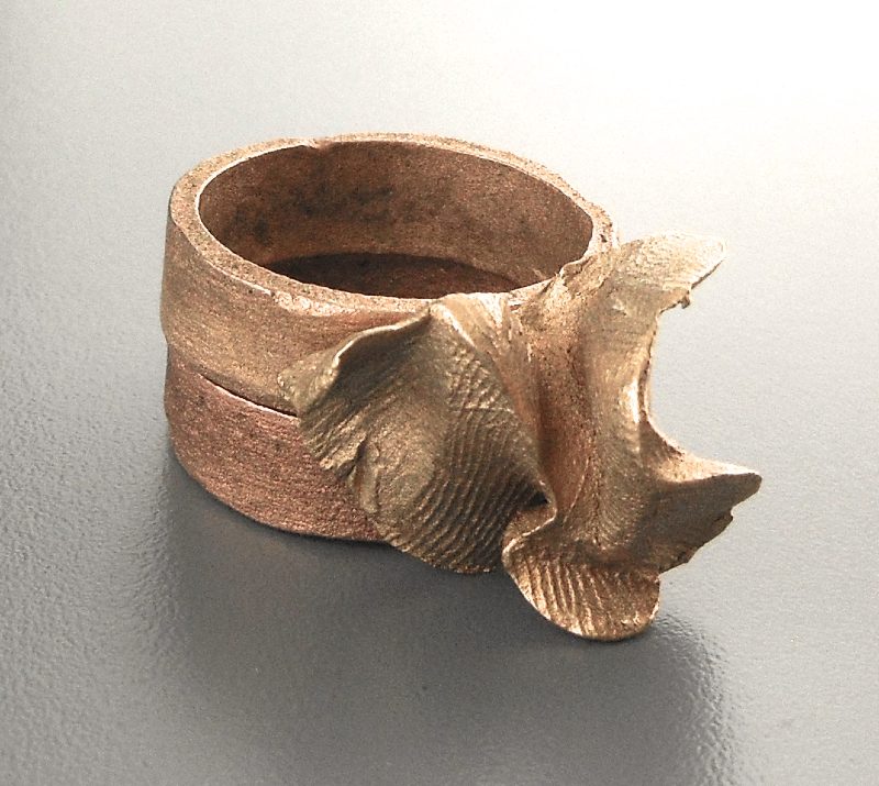 Ring of two bands topped with an abstract flower, colors shading from bronze-gold to red-gold