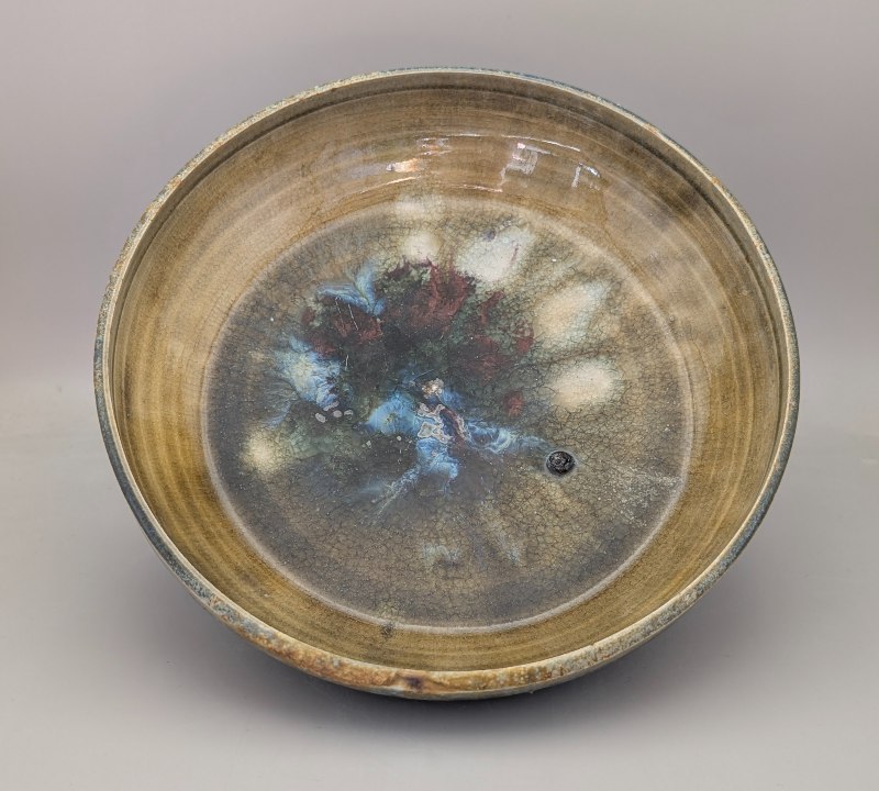 Interior of large round bowl glazed in subtle shades of light brown, blue, and burgndy