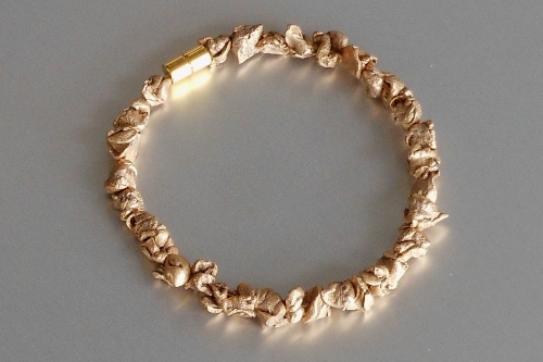 Circular bracelet of irregularly shaped, rough-textured beads of polished bronze