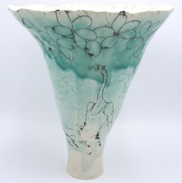 V-shaped vase in shades of turquoise and cream with line drawings of flower blossoms and seated woman with the head of a flamingo