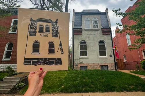 Street scene of old two-story house with block print portrait of the house being held next to it, with person's hand showing, so that the house in the print appears to be the same size as the actual house